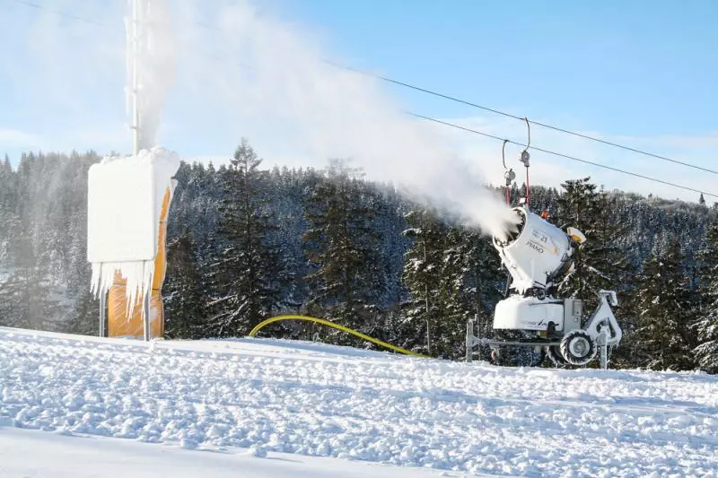 Schneekanone im Betrieb auf einer verschneiten Skipiste